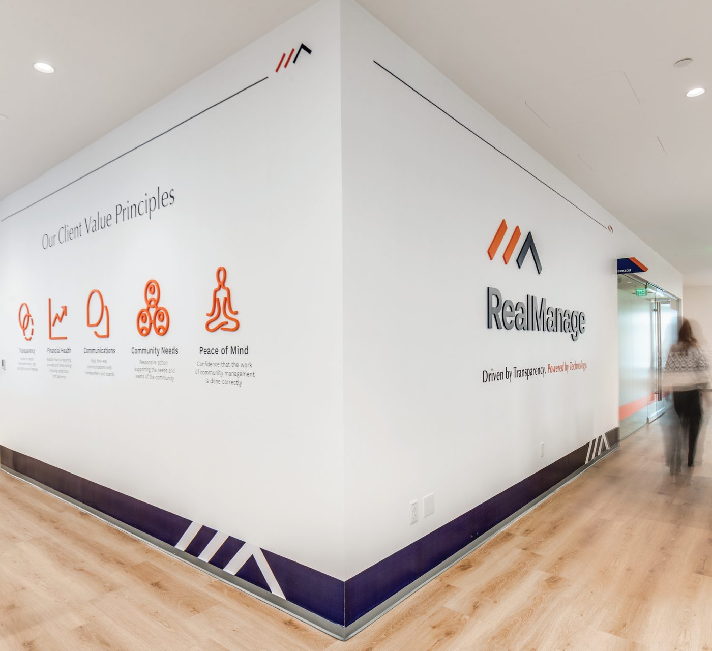 White corner office wall with orange icons and a purple floor band