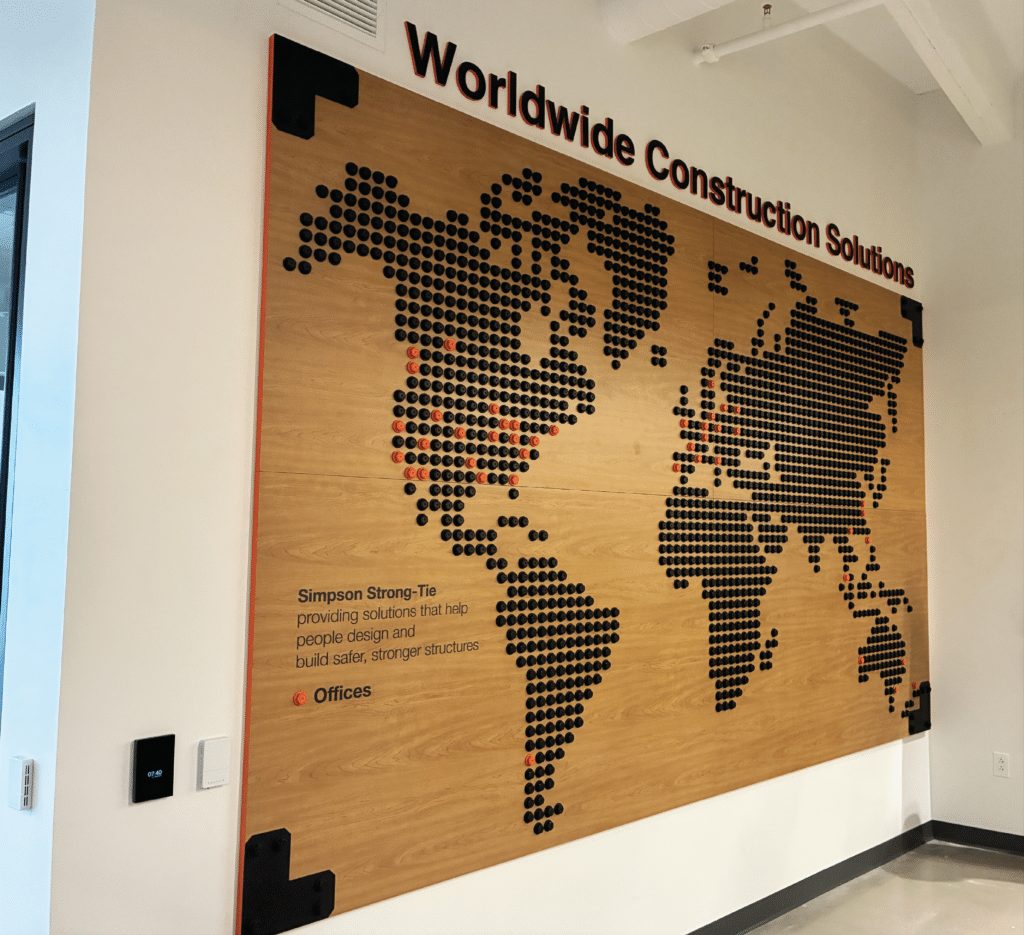 World map made of hundreds of black discs on a wooden wall